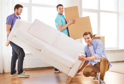 Movers carrying furniture through a shared hallway in Bromley