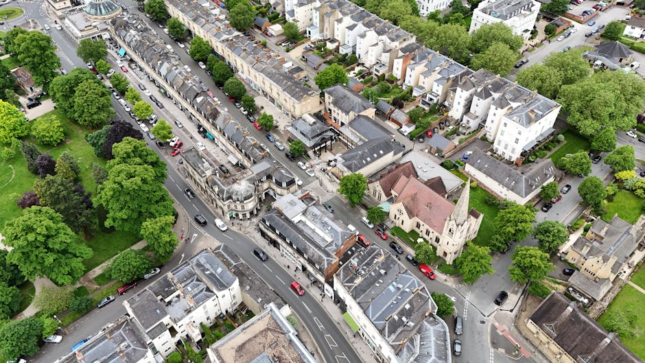 An aerial view of a typical residential street in Bromley, showing tightly packed terraced houses with varied roof styles and colours, lined with parked cars along both sides of the road. There are gr